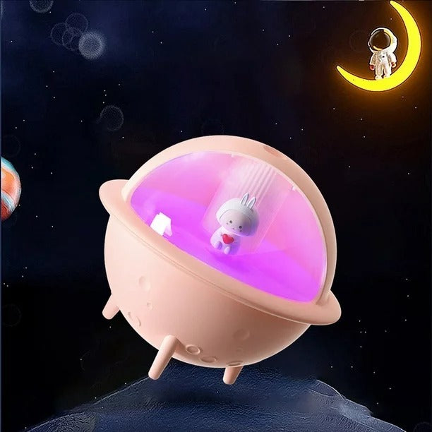 Luz nocturna LED con diseño de nave espacial y figura de conejito en el interior, emitiendo una suave luz púrpura. Ideal para decoración de habitaciones infantiles, creando un ambiente tierno y mágico con temática espacial.