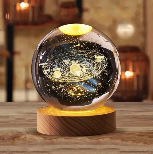 Lámpara decorativa con forma de globo, mostrando un diseño del sistema solar iluminado en la base de madera.